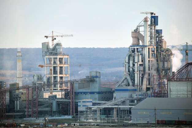 Fábrica de cimento com estrutura fabril alta e guindastes de torre na área de produção industrial