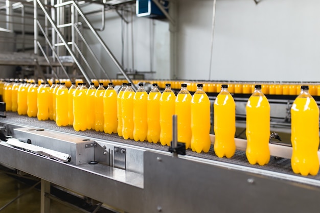 Fábrica de embotellado - Línea de embotellado de jugo de naranja para procesar y embotellar jugo en botellas. Enfoque selectivo.