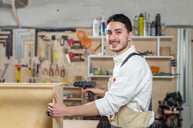 Fábrica de muebles, pequeñas empresas y concepto de personas - Joven trabajador trabaja en una fábrica para la producción de muebles.