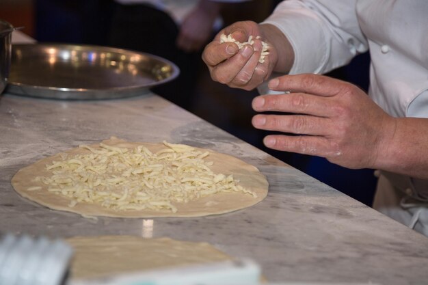 Foto fabricante de pizzas que prepara uma deliciosa pizza com queijo e alcaparras