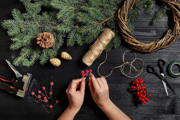 Fabricante de decoración navideña con sus propias manos. Corona de Navidad para las vacaciones. La celebración del año nuevo. Clase magistral de elaboración de adornos decorativos. Vista superior. Endecha plana