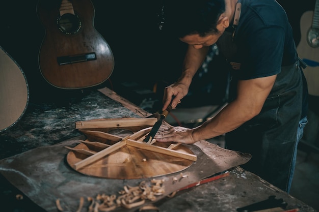 Fabricantes de guitarras homem asiático fazendo guitarras acústicas em laboratório Fabricante de guitarras asiáticas constrói guitarras de alta qualidade para músicos loja de guitarras artesanais Trabalhando bem a tradição woodusic artesanato antigo