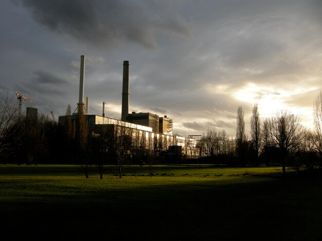 Foto fabrik auf grasigem feld gegen bewölkten himmel