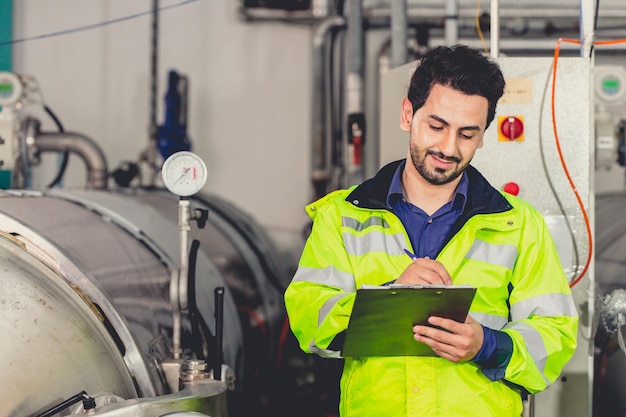 Fabrikarbeiter arabischer hispanischer Ingenieur, der in der Fabrik arbeitet und das Wartungsrohrkesselsystem in der Fabrik überprüft