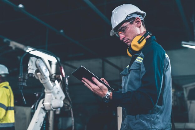 Fabrikarbeiter, die in einer Werkstatt mit einem geschickten Roboterarm arbeiten