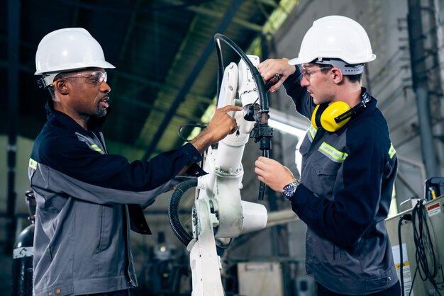 Fabrikarbeiter, die in einer Werkstatt mit einem geschickten Roboterarm arbeiten