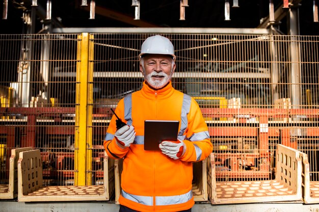 Fabrikarbeiter in Sicherheitsuniform und weißem Schutzhelm, der in der Fertigungsfabrik steht