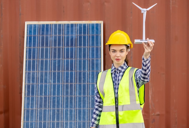 Fabrikarbeiter oder Ingenieure, die mit Windmühlenmodell auf Sonnenkollektoren halten,