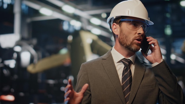 Fabrikdirektor spricht am Telefon in einer Metallurgieanlage. Engineer ruft aus.