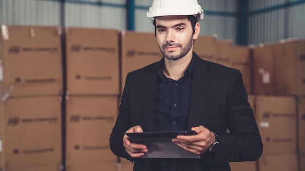 Fabrikmanager mit Tablet-Computer im Lager oder in der Fabrik. Industrie- und Supply-Chain-Management-Konzept.