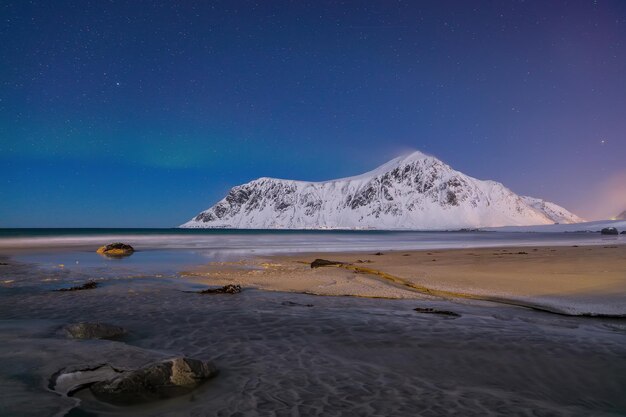 Fabulosa paisagem de inverno na praia de Skagsanden à noite com as luzes do norte