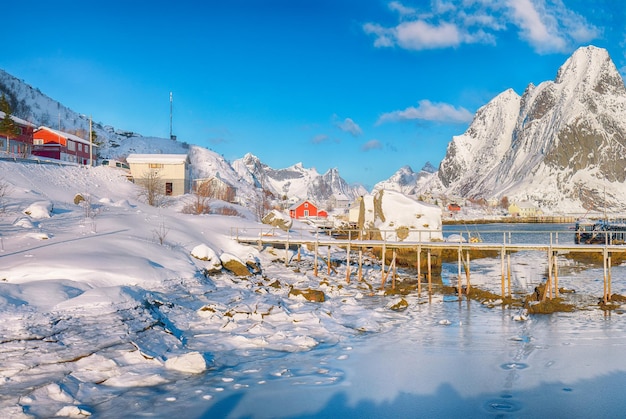 Fabulosa vista soleada de invierno en Reine Village y pasarela sobre la bahía de Gravdabukta con hielo agrietado
