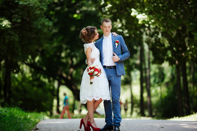 Fabuloso casal jovem casamento posando no parque no dia ensolarado.