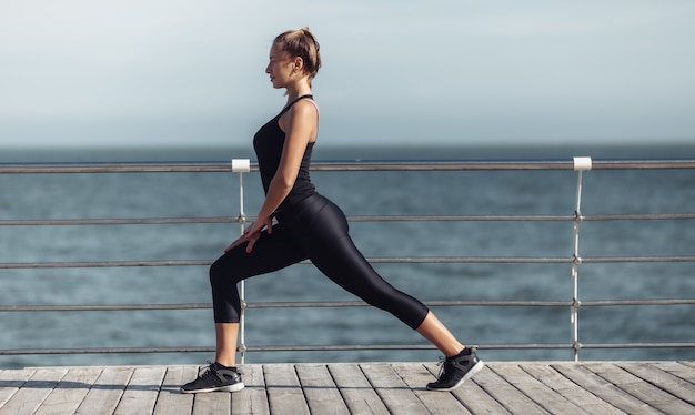 Faça aquecimento antes do treino. Jovem magro com corpo perfeito fazendo aeróbica