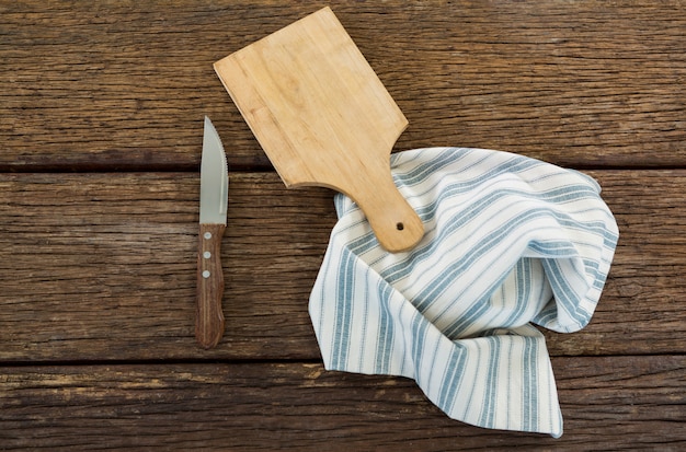 Foto faca, bandeja de madeira e toalha de mesa