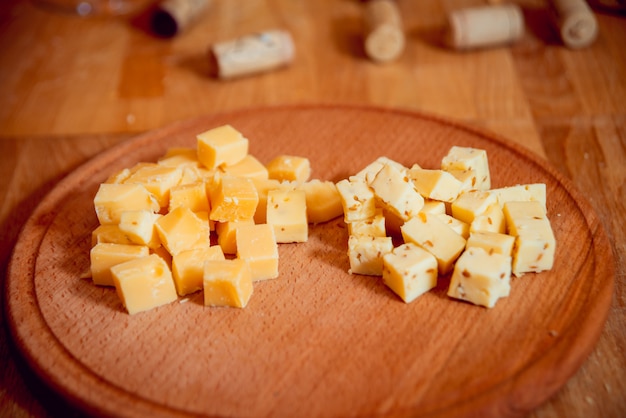 Faca com pedaço de queijo em uma mesa escura