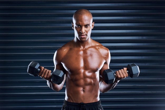 Faça da persistência um hábito Foto de um jovem esportivo malhando com halteres como parte de sua rotina de exercícios