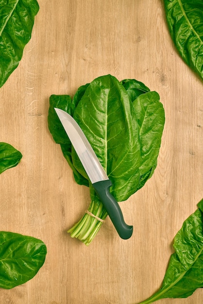 Faca de chefs e folhas verdes frescas em um balcão de cozinha de madeira pronto para fazer uma salada de dieta.
