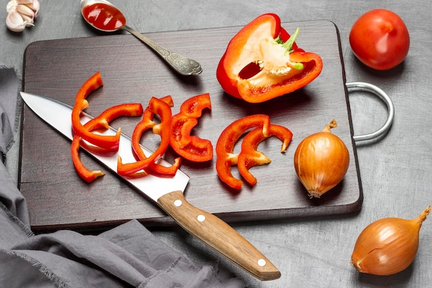 Faca de cozinha picada pimenta vermelha e meia pimenta na tábua alho e colher com molho de tomate