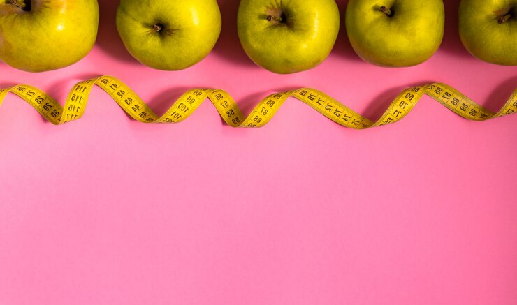 Foto faça dieta o conceito com maçã verde e trena na fila no fundo rosa