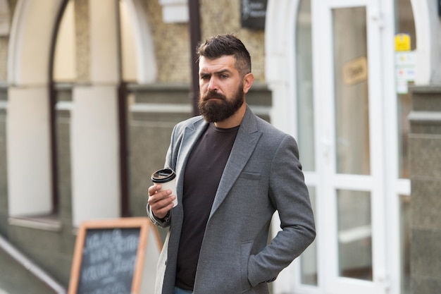 Faça este dia com café. Homem barbudo, apreciando o café da manhã. Bebendo seu copo logo pela manhã. Empresário em estilo hipster segurando café para viagem. Hipster com copo de papel andando na cidade.