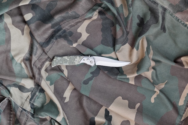 Foto faca militar em roupas de camuflagem do exército close-up. parede com espaço de cópia para projeto militar ou de operações especiais