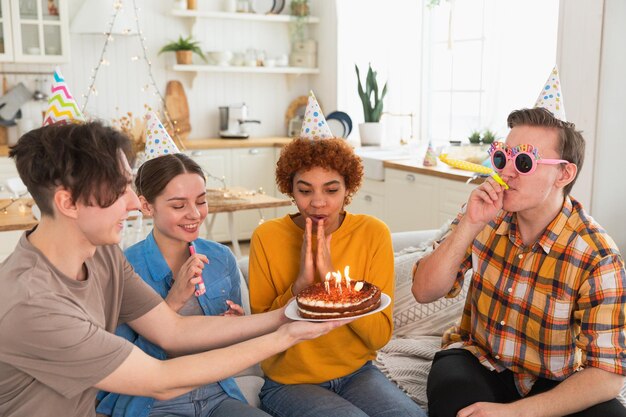 Foto faça um desejo, mulher usando boné de festa, soprando velas acesas no bolo de aniversário, feliz aniversário