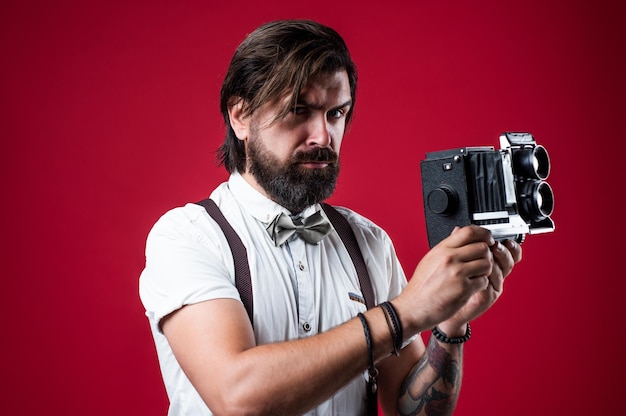 Faça uma pose elegante homem segurando câmera retro bonito hipster fazendo foto vintage jornalista maduro use tecnologia antiga câmera barbuda homem em suspensórios cara brutal fotógrafo use gravata borboleta