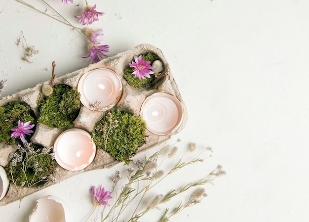 Faça você mesmo para a páscoa. cascas de ovos com velas em um fundo branco com flores do campo.