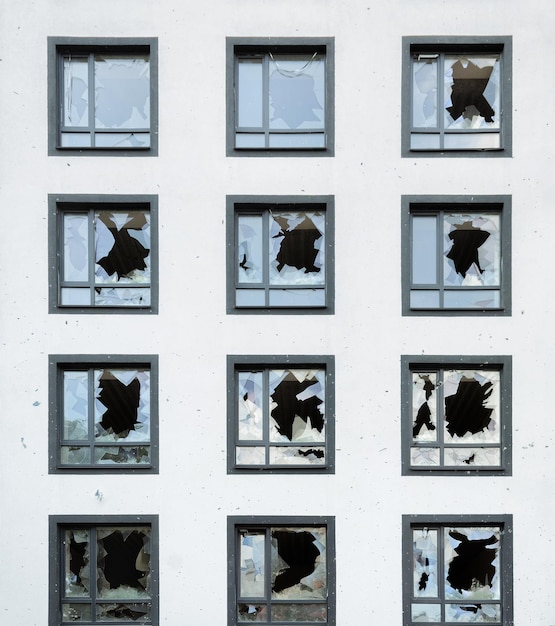 Facada de uma casa residencial com janelas quebradas e danos causados por fragmentos de minas e projéteis