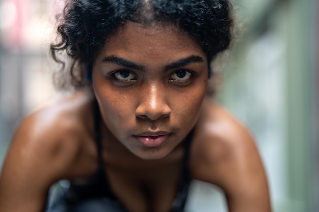 Face aproximada de uma mulher africana atlética forte, corredora de olhos negros, sentindo-se concentrada correndo no fundo da cidade, usando roupas esportivas Conceito de corredor de motivação esportiva e fitness