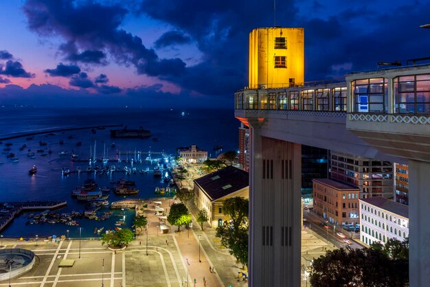 La fachada del ascensor de Lacerda iluminada por la noche con la ciudad y los barcos en la ciudad de Salvador Bahia