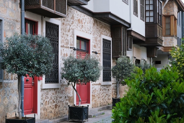 Fachada de una casa antigua hecha de piedras y hormigón con puertas de entrada y balcones rojos