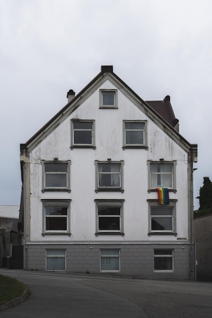 fachada de una casa histórica con una bandera LGBT en la ventana