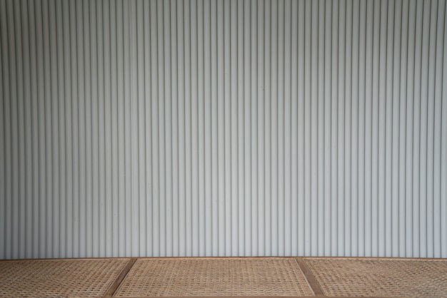 Foto fachada de chapa de madera corrugada en color blanco con banco de mimbre superior vacío