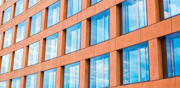 Fachada de cristal moderna de un edificio de oficinas, reflejo del cielo en las ventanas.