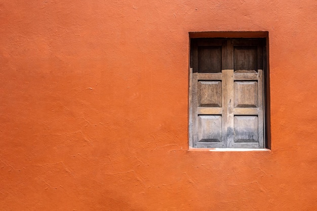 Fachada da casa de parede laranja resistida, janela de madeira na rua da cidade velha