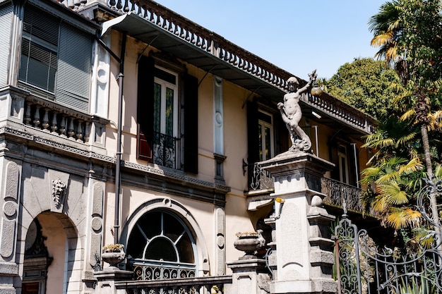 Fachada de prédio luxuoso com cerca de metal e estátuas de pedra como a Itália