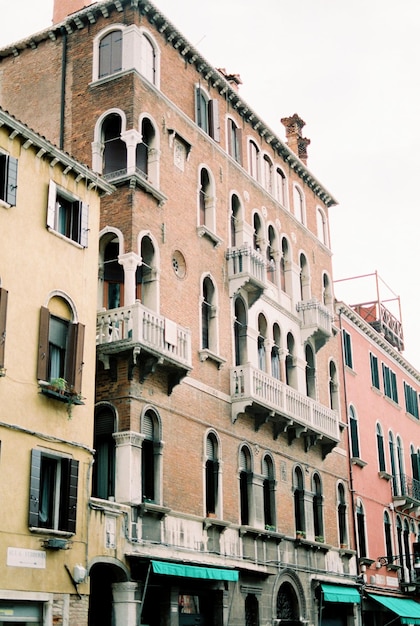 Fachada de um antigo edifício de tijolos com janelas arqueadas e varandas em veneza