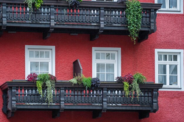 Fachada de um prédio antigo com varanda de madeira e flores em uma parede de pedra vermelha em uma rua na Áustria Europa