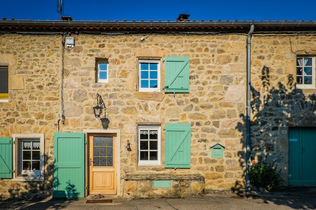 Fachada de uma bela casa de pedra em boucieu le roi (ardeche, frança) com persianas azuis