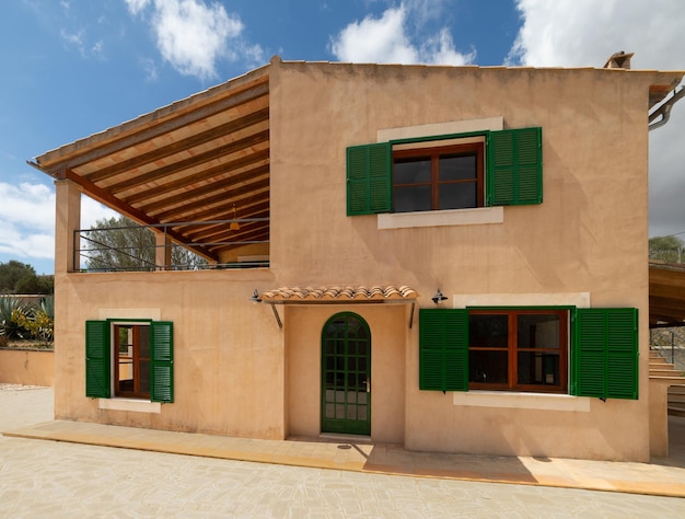 Fachada de uma casa de campo com janelas verdes e terraço em uma casa de campo em Maiorca, Espanha