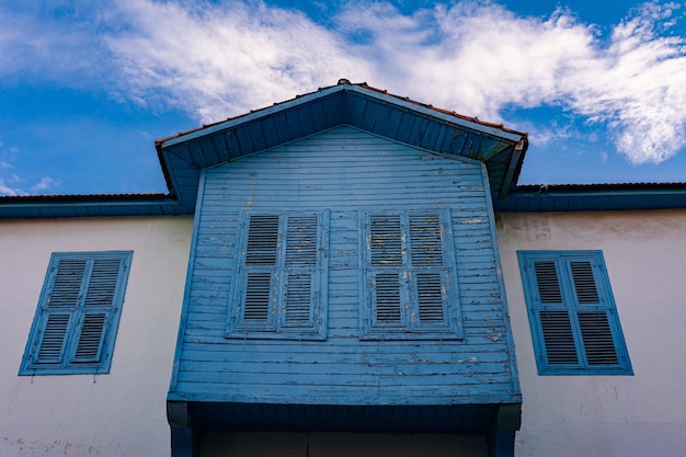 Fachada de uma casa vintage com varanda e persianas contra o céu