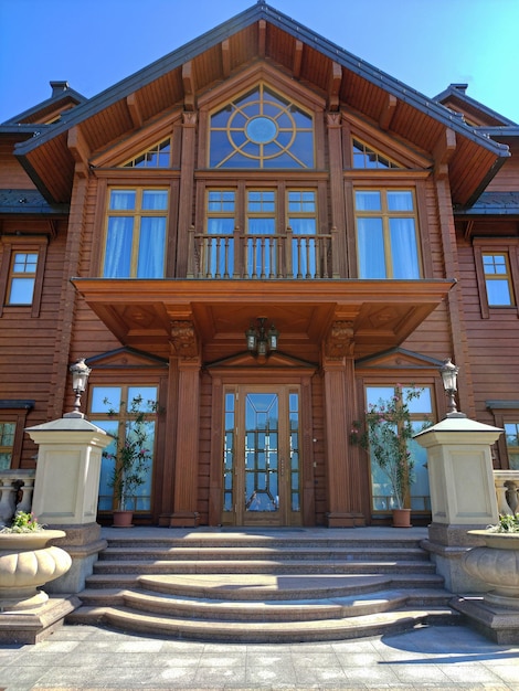 Fachada de uma grande casa de luxo de dois andares de madeira com escadas de mármore e lâmpadas de rua
