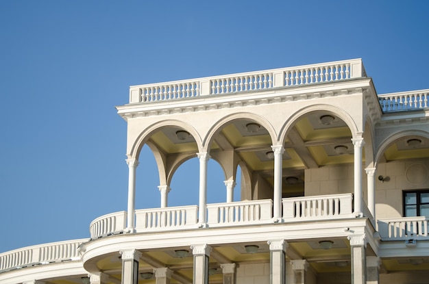 Fachada do edifício branco com arcos e varandas na perspectiva do céu azul