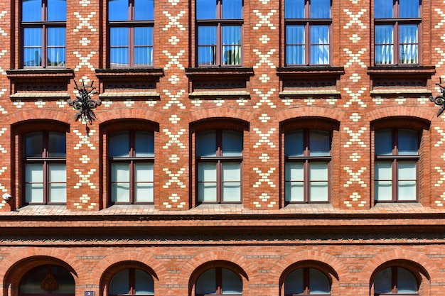 Fachada do edifício histórico com janelas azuis e uma parede de tijolos vermelhos Poznan Polónia