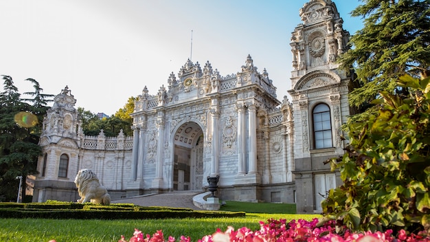 Fachada do palácio dolmabahçe com jardins repletos de vegetação e flores em frente a ele em istambul, turquia