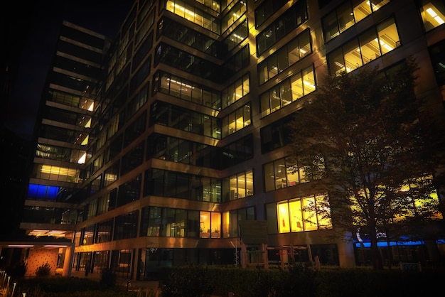 Fachada do prédio de escritórios com janelas iluminadas no distrito do centro da cidade de Varsóvia à noite com céu