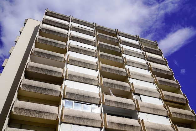 Fachada de edificio de apartamentos en un día soleado con un cielo nublado azul