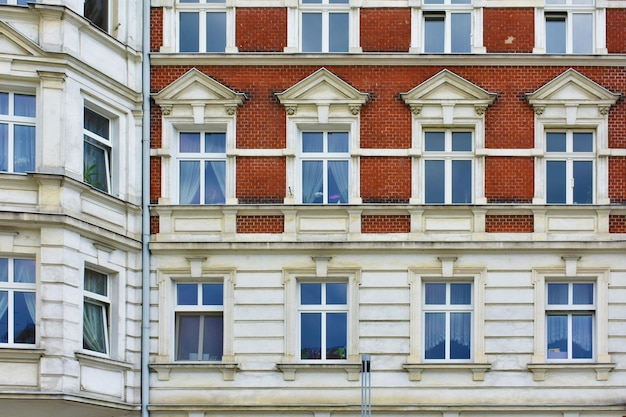 Fachada del edificio histórico con ventanas azules paredes de ladrillo rojo y blanco Polonia Poznan